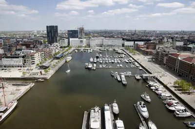 Flusskreuzfahrt Thurgau Hafen Antwerpen Ein Flusskreuzfahrtschiff von Thurgau Reisen im Hafen von Antwerpen während des Bunkerns. Das Schiff liegt an der Pier, während Besatzungsmitglieder mit dem Beladen von Treibstoff und Vorräten beschäftigt sind. Im Hintergrund sind die charakteristischen Gebäude des Hafens und die geschäftige Atmosphäre der Hafenaktivitäten sichtbar.