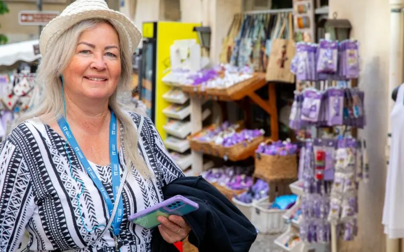 Ausflug in Avignon Single Eine Passagierin von Thurgau Reisen beim Landgang in Avignon. Sie trägt einen Strohhut und lächelt, während sie in einem kleinen Markt mit bunten Souvenirs und lokalen Produkten steht. Im Hintergrund sind Regale mit Lavendel und anderen typischen regionalen Artikeln zu sehen, die die charmante Atmosphäre der Stadt unterstreichen.