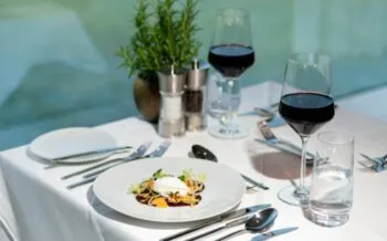 Abendessen als Menügang auf der Thurgau Gold. Man sieht einen gefüllten Teller und Gläser mit Rotwein sowie Besteck, Pfeffer und Salz.