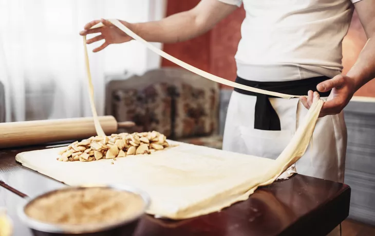 Male chef prepares dough for apple strudel