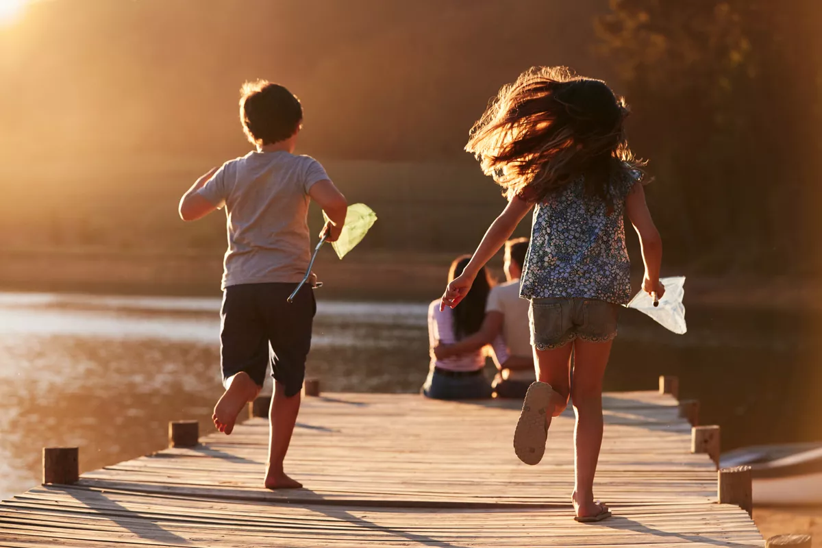 Kinder laufen auf hölzernen Steg am See auf Eltern zu - © Monkey Business - stock.adobe.com