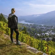 Wanderin genießt den Sonnenaufgang über einer kleinen europäischen Stadt Winningen, Deutschland mit Weinbergen im Rheintal
