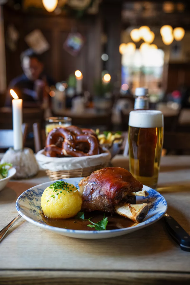 Traditionelle Schweinshaxe mit Knödel und Bier im gemütlichen Wirtshaus - © NIKIBA - stock.adobe.com